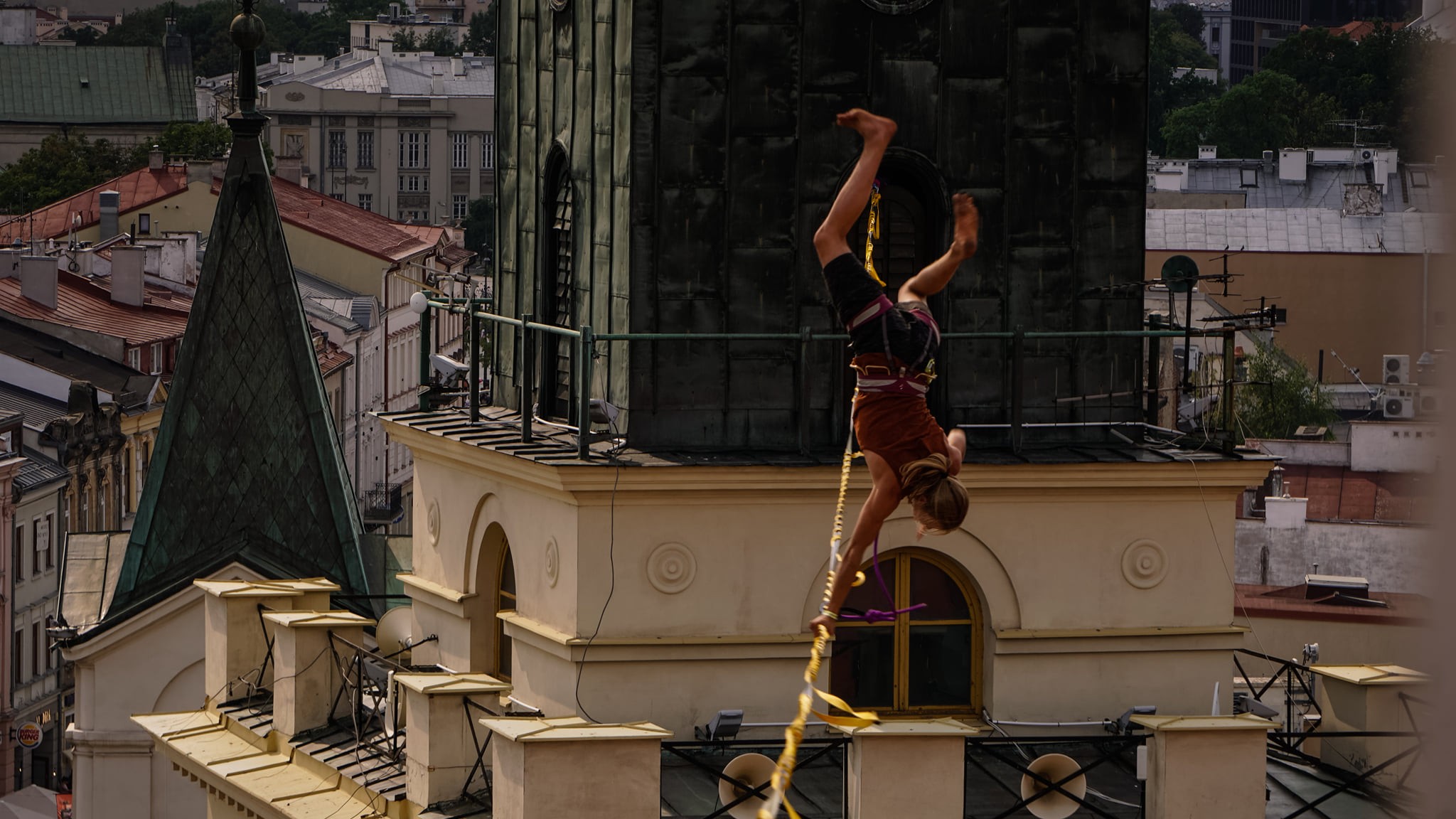Slackliner führt in großer Höhe einen Handstand auf einer Slackline zwischen historischen Gebäuden in der Stadt aus.
